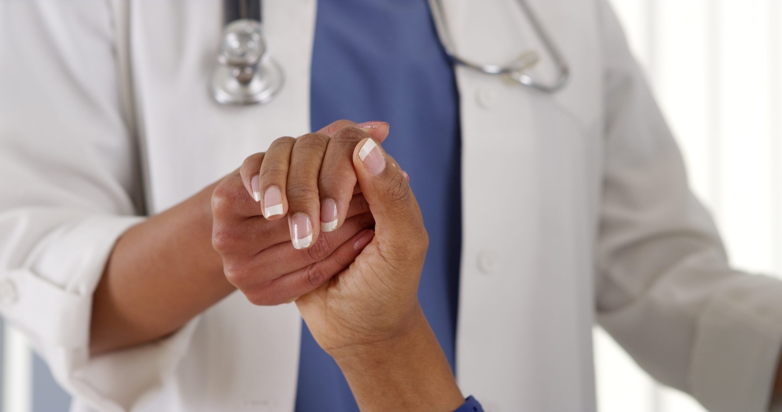 Close up of female African American doctor holding patient's hand